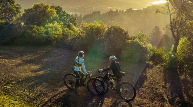 Deux cyclistes se tiennent dans les montagnes et regardent la vallée.