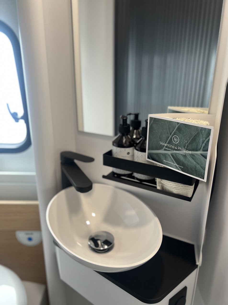 Baño pivotante con lavabo y cosmética ecológica Adria Twin 640 SGX | Activans Zona de lavabo en el baño pivotante amplio Adria Twin 640 SGX con productos de cosmética ecológica Valentina & Philippa Organic Body Care – alquilar furgoneta camper Costa Brava