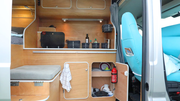 View inside the living area of the camper van. You can see the bench seat and the kitchenette.
