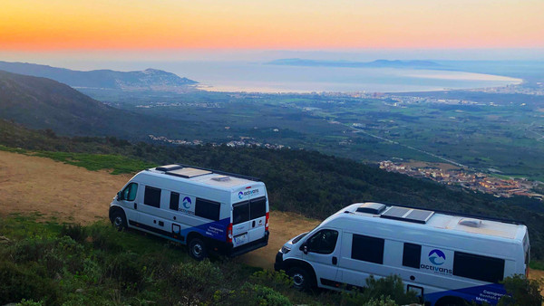 [Translate to German:] Two vans overlook the bay of Roses with sunrise