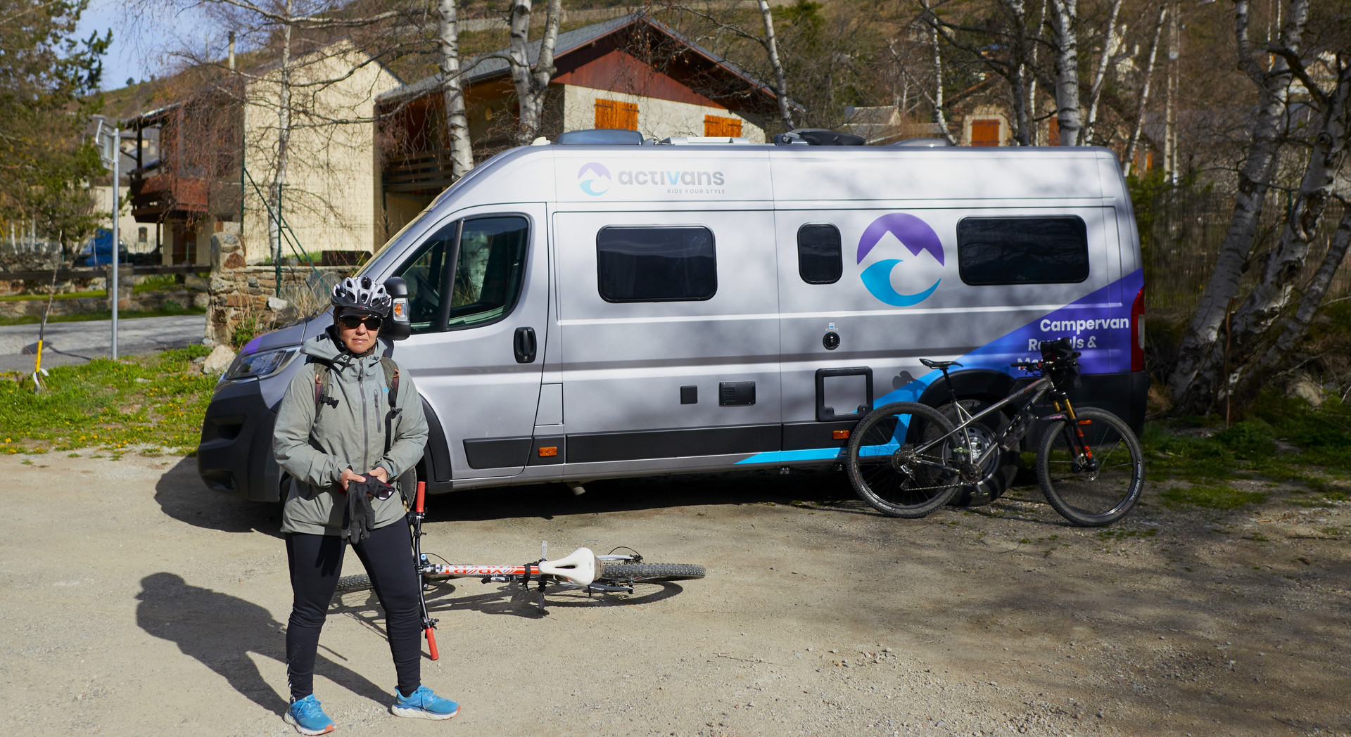 woman stands with her two bikes in front of the motorhome