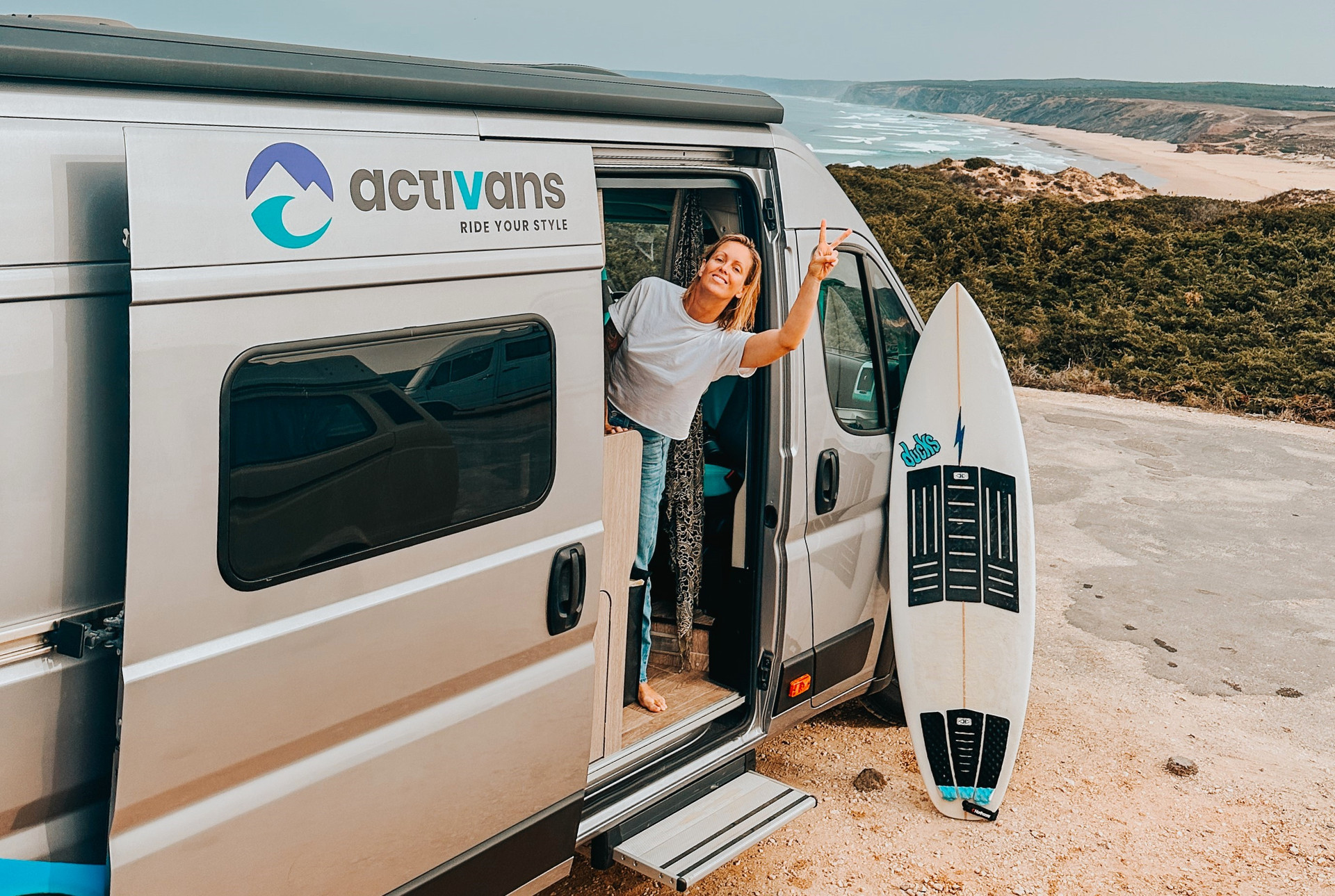 Einer Surferin steht in der Tür eines Activans Campers am Strand in Portugal.