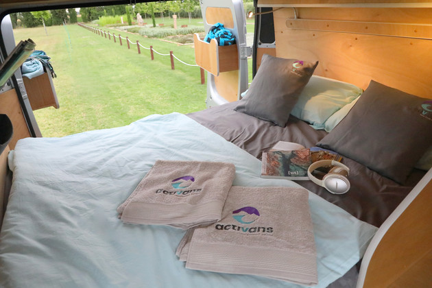 The 140-metre-wide bed is made up for 2 people. There are 2 towels embroidered with the Activans logo laying on the duvet.
