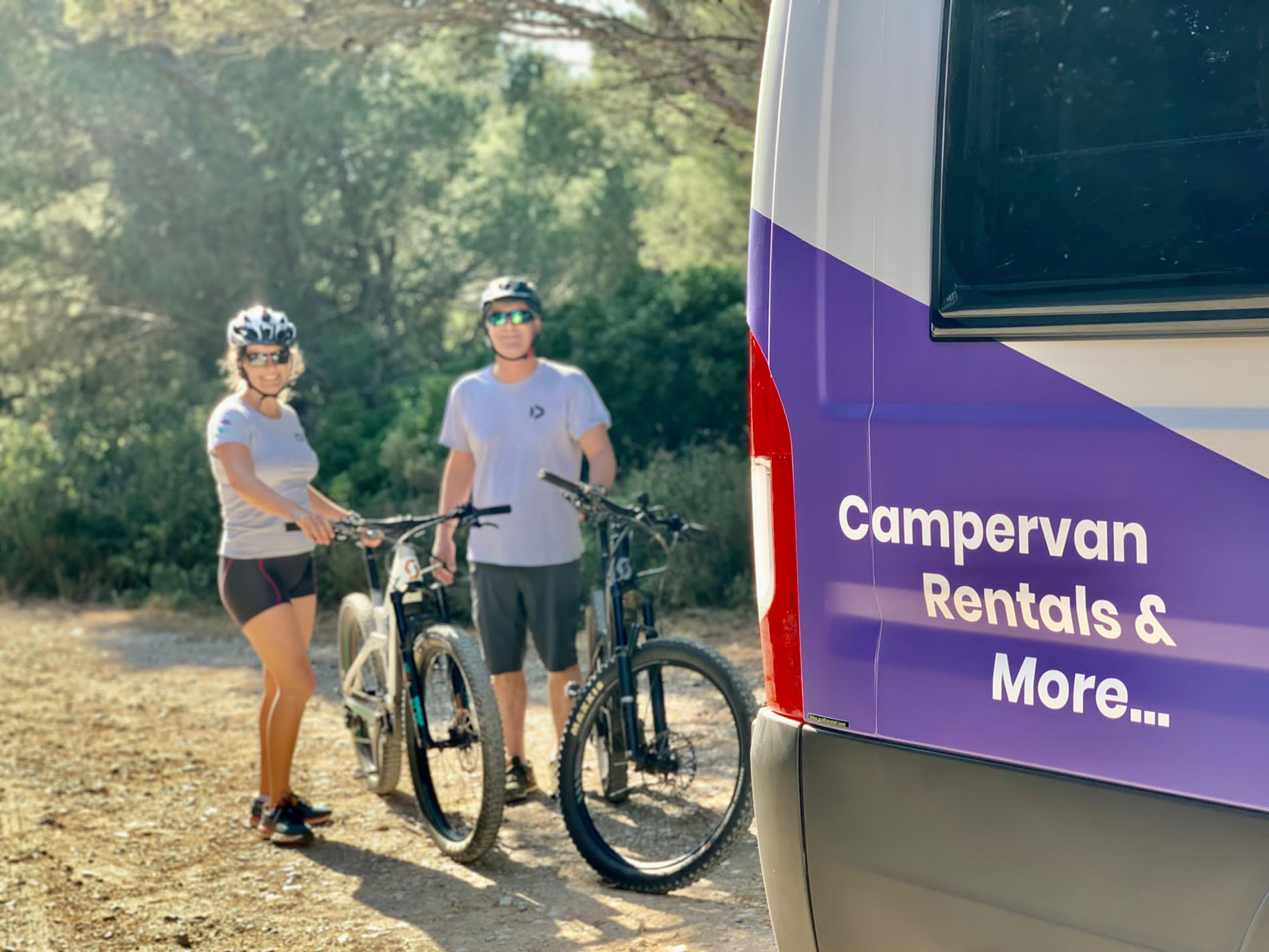 Zwei Radfahrer stehen neben mit ihren Bikes hinter dem Campervan