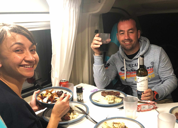 [Translate to German:] two people having dinner inside the campervan