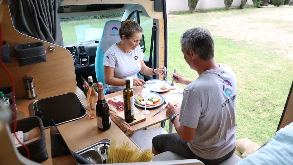 two people sitting inside and having dinner in the camper van 
