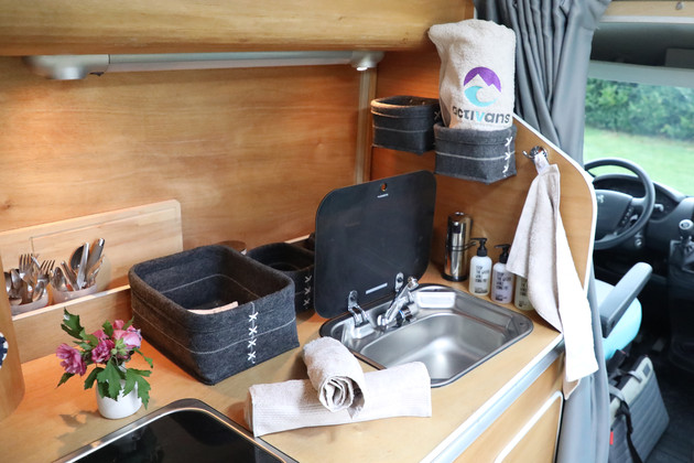 Das Waschbecken des Campervans mit ökologischen Kosemetikprodukten und Handtüchern mit Activans Logo ausgestattet